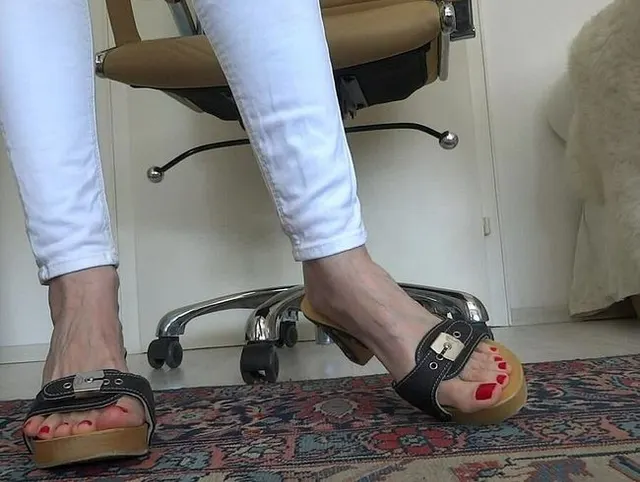 Holzpantoletten und Füße mit roten sexy Fußnägeln