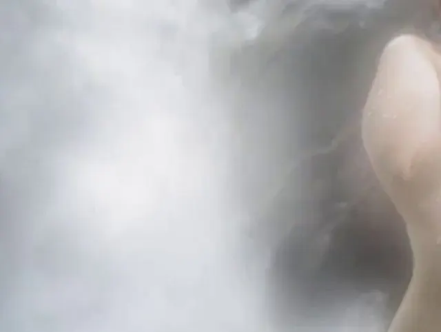Sie zieht sich am Wasserfall im Freien aus